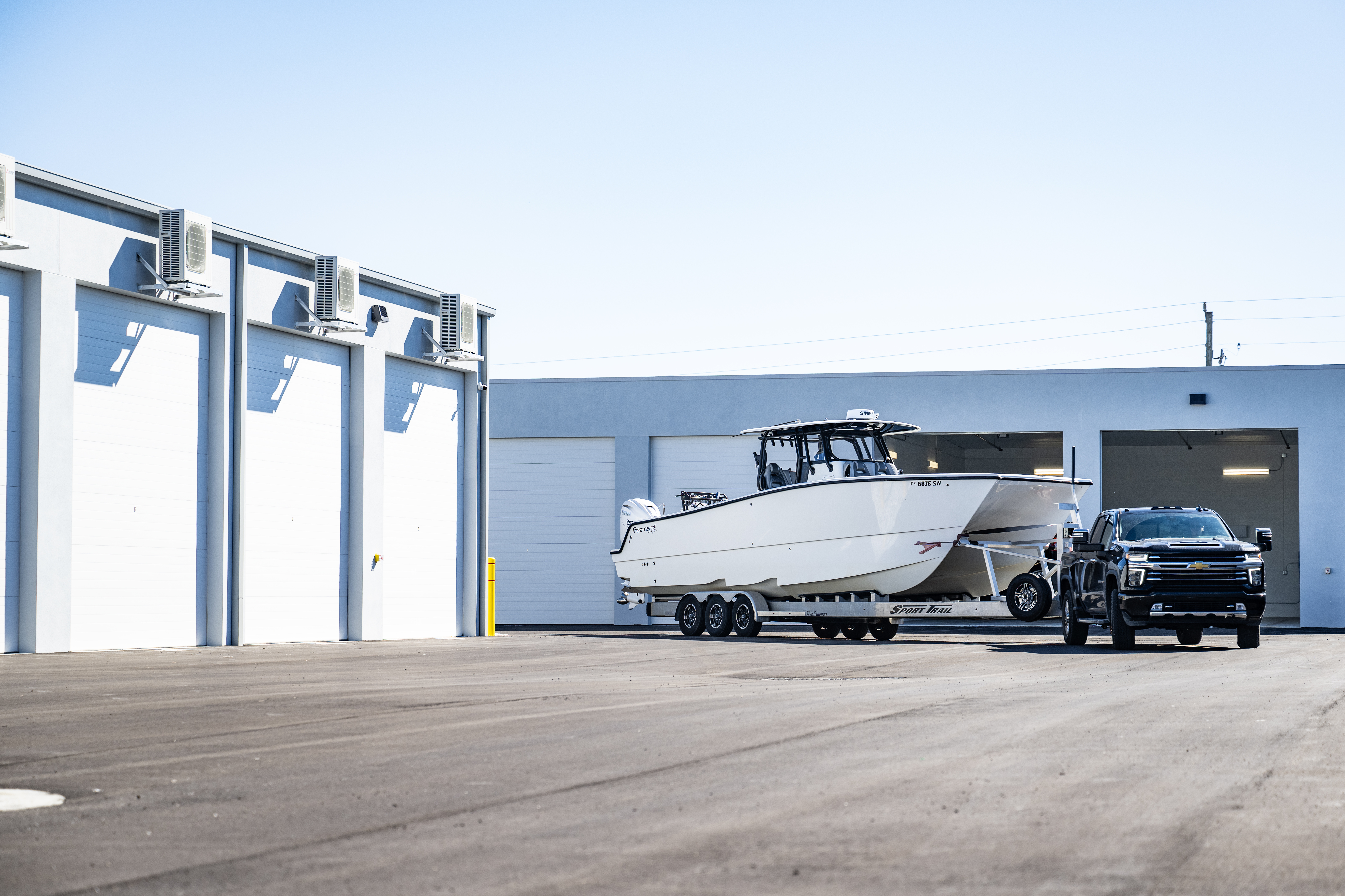 Truck towing a large center-console boat positioned in front of private climate-controlled storage units at MetroMaxx RV & Boat Storage in Fort Myers, Florida
